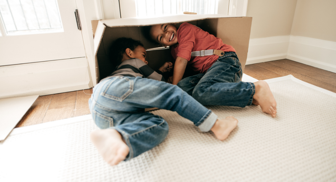 two boys playing on the floor in a cardboard box. Winter Reset. Des Moines Mom