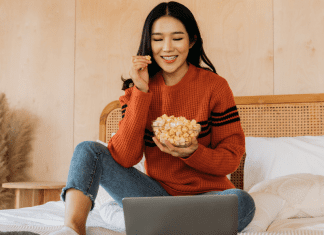 woman on bed with popcorn watching movie. Des Moines Mom