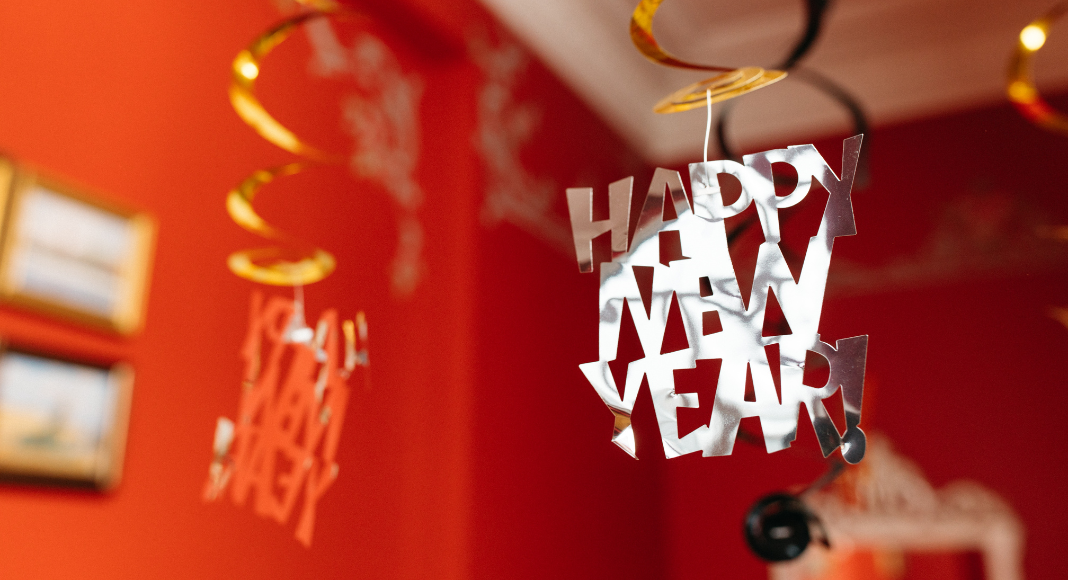 Red walls in a living room with a Happy New Year sign hanging from the ceiling. New Years Eve ideas