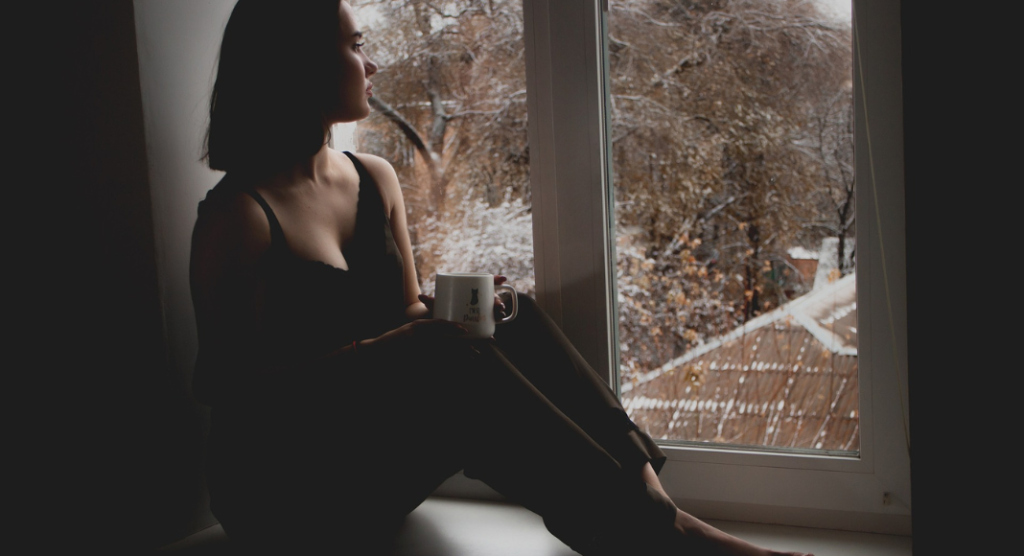 woman staring out window. Seasonal Affective Disorder
