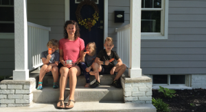 kids and woman sitting on front steps of home