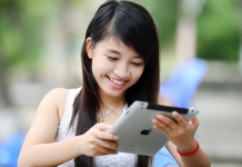 girl with black hair looking at ipad and smiling