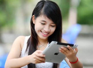 girl with black hair looking at ipad and smiling