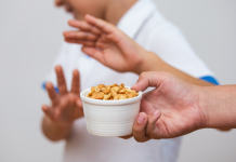 white bowl of nuts and kid pushing them away. food allergy
